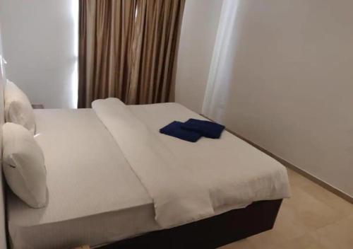 ein Schlafzimmer mit einem weißen Bett mit einem blauen Objekt darauf in der Unterkunft Areia De Goa - Sunrise By Leela Homes in Arpora