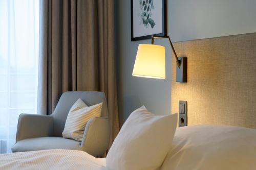 a bedroom with a bed and a chair and a lamp at Hotel am Kloster in Werne an der Lippe