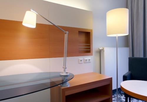 a desk with a lamp on it next to a chair at Hotel am Kloster in Werne an der Lippe