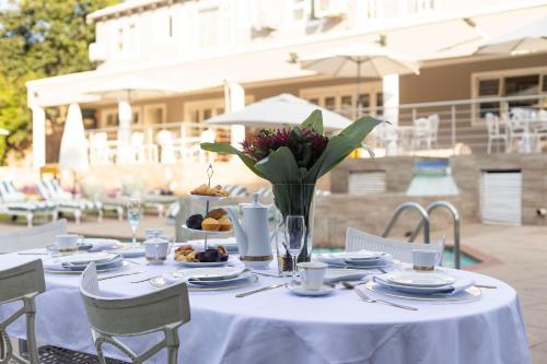 a white table with plates of food and flowers on it at Dikalo Highston Boutique Guest house in Bryanston Sandton Johannesburg in Johannesburg