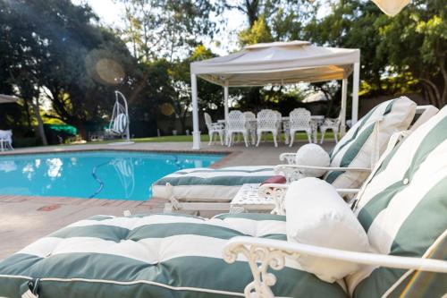 a group of chairs next to a swimming pool at Dikalo Highston Boutique Guest house in Bryanston Sandton Johannesburg in Johannesburg