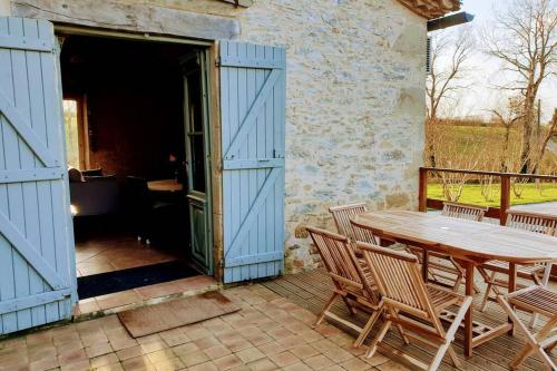 einen Holztisch und Stühle auf einer Terrasse in der Unterkunft GITE AU COEUR DE LA CAMPAGNE in Saint-Sève