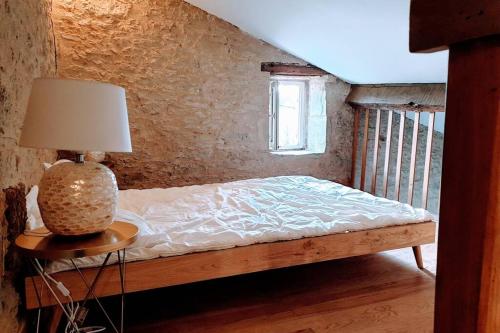 um quarto com uma cama e um candeeiro sobre uma mesa em GITE AU COEUR DE LA CAMPAGNE em Saint-Sève