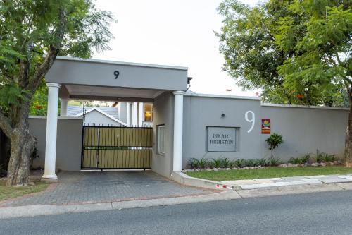 a white house with a gate and a driveway at Dikalo Highston Boutique Guest house in Bryanston Sandton Johannesburg in Johannesburg