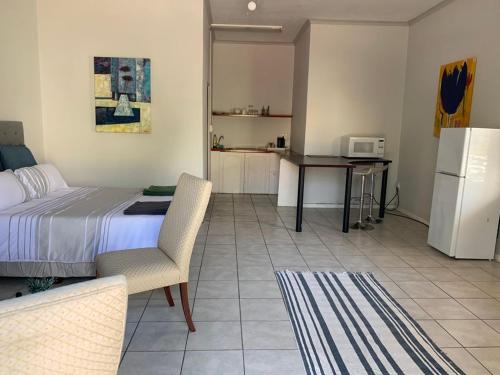 a bedroom with a bed and a table and a refrigerator at Le Grec Wine Tram Apartment in Franschhoek