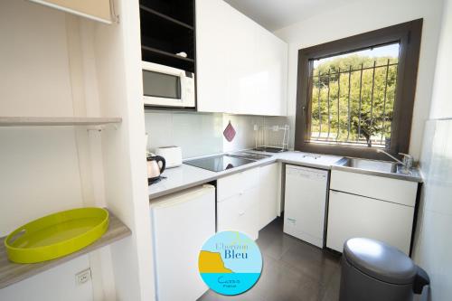 una pequeña cocina con armarios blancos y una ventana en HORIZON BLEU Vue Mer, en Cassis