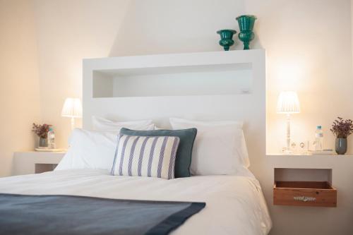 a bedroom with a bed with white sheets and pillows at Casa Shelly Hospedería in Vejer de la Frontera