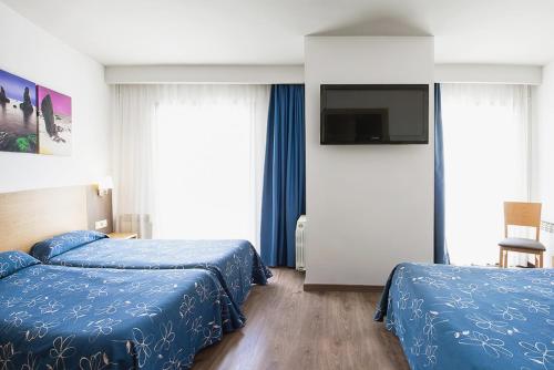 a hotel room with two beds and a flat screen tv at Hotel Acapulco in Lloret de Mar
