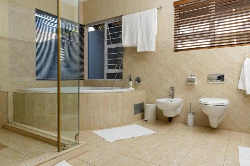 a bathroom with a toilet and a tub and a sink at Dikalo Highston Boutique Guest house in Bryanston Sandton Johannesburg in Johannesburg