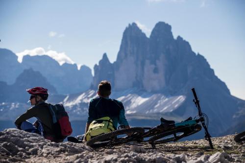 two men sitting on top of a mountain with a bike at Boutique & Gourmet Hotel Orso Grigio in San Candido