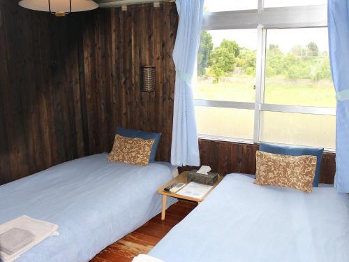 two beds in a room with a window at Guest House Miyakojima in Miyako-jima
