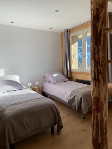 une chambre avec deux lits et une fenêtre dans l'établissement La marmotte qui papote, au Grand-Bornand