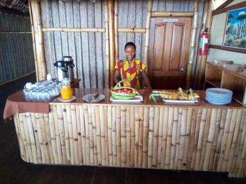een man achter een toonbank met eten bij Barry's Beach Resort in Mkwaja