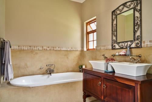 a bathroom with two sinks and a tub and a mirror at Haus Schwerinsburg Guest House in Windhoek