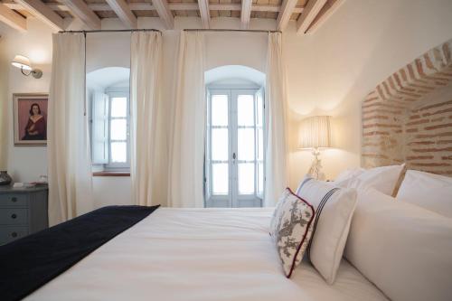 a bedroom with a large white bed with white pillows at Casa Shelly Hospedería in Vejer de la Frontera