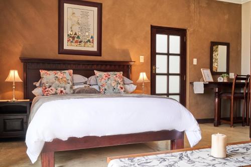 a bedroom with a large bed and a desk at Haus Schwerinsburg Guest House in Windhoek