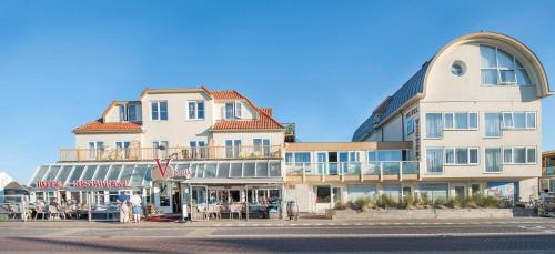 ein hohes Gebäude mit Tischen und Stühlen davor in der Unterkunft Hotel Victoria in Bergen aan Zee
