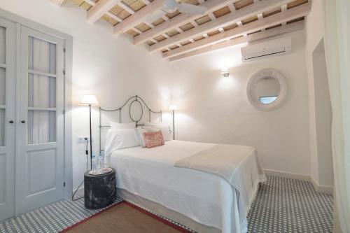 a white bedroom with a bed and a window at Casa Shelly Hospedería in Vejer de la Frontera