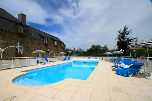 une grande piscine avec des chaises bleues et un bâtiment dans l'établissement Hotel Spa La Malouinière Des Longchamps - Saint-Malo, à Saint-Jouan-des-Guérets