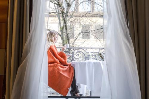a woman sitting at a table looking out a window at Hotel St.Gotthard in Zürich