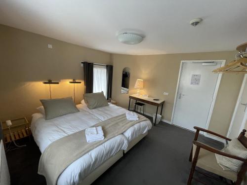 a bedroom with a large bed and a desk at In den Roden Leeuw van Limburg in Wittem