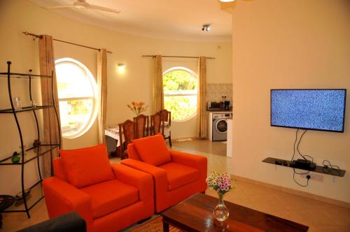 a living room with an orange chair and a television at Victoria Lake View Guesthouse & Safaris in Entebbe