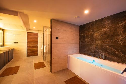 a bathroom with a tub and a glass shower at Hometown Galleria Manipal in Manipal