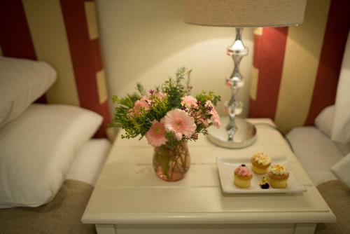 a table with a vase of flowers and cupcakes on it at Last Word Constantia in Cape Town