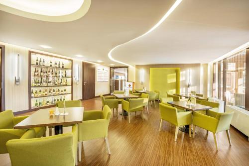 a restaurant with yellow chairs and tables and tablesktop at Hotel Europa Fit Hévíz in Hévíz