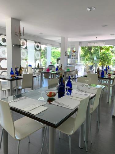 un comedor con sillas y mesas blancas y botellas azules en Villa Liliana, en Cervia