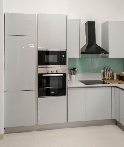 Una cocina con gabinetes blancos y electrodomésticos negros. en Clayhall by SRS, en Lagos