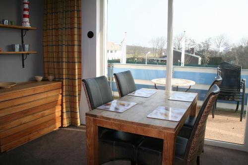 ein Esszimmer mit Tisch und Stühlen und einem Fenster in der Unterkunft Schorrebloem 1 in Nieuwvliet