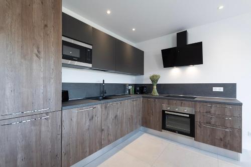 a kitchen with wooden cabinets and a sink and a tv at Résidence U Manellu in Santa-Reparata-di-Balagna