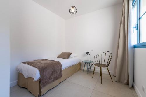 a white bedroom with a bed and a chair at Résidence U Manellu in Santa-Reparata-di-Balagna