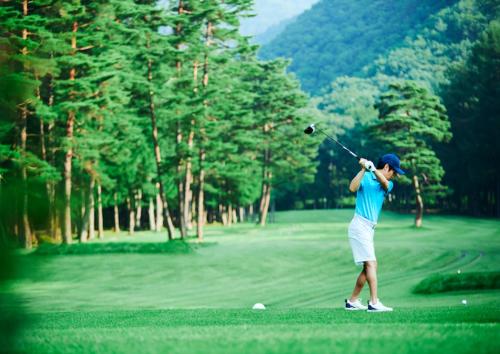 a man swinging a golf club on a golf course at Holiday Inn Resort Shinano-Omachi Kuroyon by IHG in Omachi
