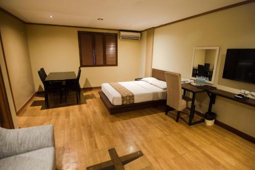 a bedroom with a bed and a desk and a television at DG Grami Hotel in Manila
