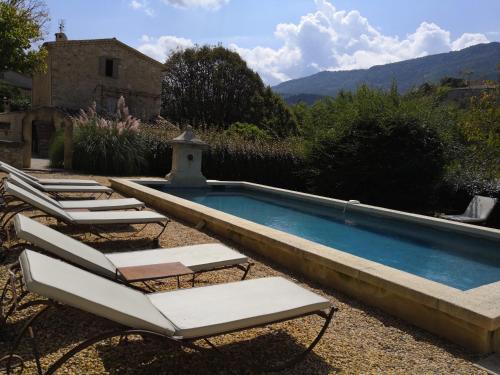 a swimming pool with lounge chairs next to a house at Mas en Baronnies Provençales in Eygaliers