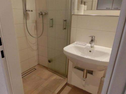 La salle de bains est pourvue d'un lavabo et d'une douche. dans l'établissement Ferienwohnung Strandperle Haus Loreley, à Sankt Peter-Ording