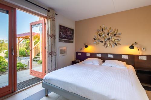 Un dormitorio con una cama y una puerta corrediza de vidrio. en Grimaud 177 - Kustpark Village Scaldia, en Hoofdplaat