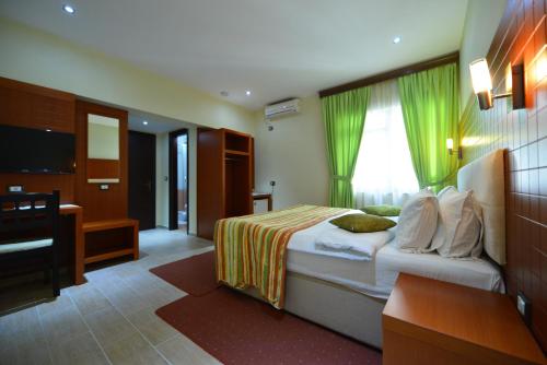 a bedroom with a bed with green curtains and a television at City Hotel in Tirana