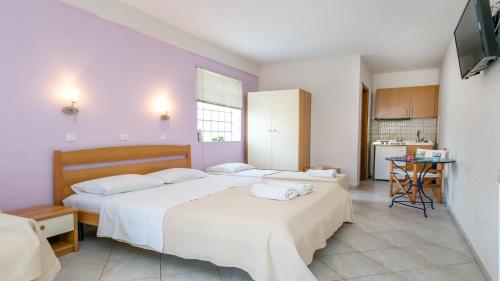 a bedroom with two beds with white sheets and a kitchen at Amversa's House in Potos