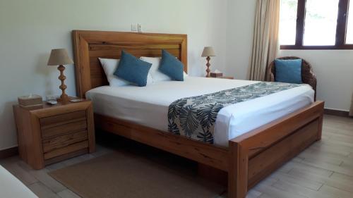 a bedroom with a large bed with blue pillows at Villa Belle Plage in Anse Kerlan