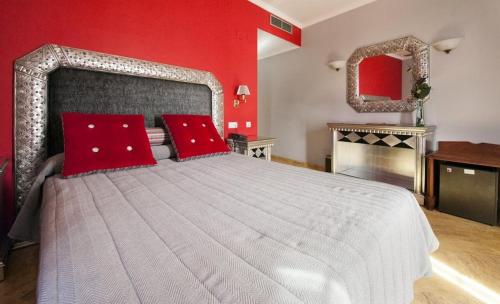 a bedroom with a large bed with red walls at Adriano Boutique Sevilla in Seville