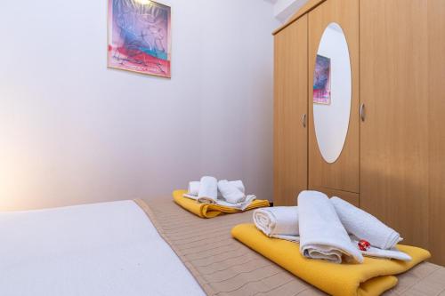 a bedroom with two beds and a mirror and towels at Apartments Grof in Selce