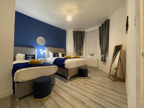 Habitación de hotel con 2 camas y pared azul en HLA Holytown, en Mossend