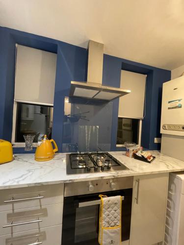 a kitchen with a stove and a blue wall at HLA Holytown in Mossend
