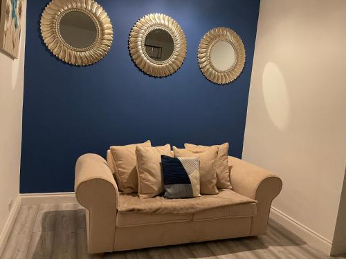a couch in a living room with three mirrors at HLA Holytown in Mossend