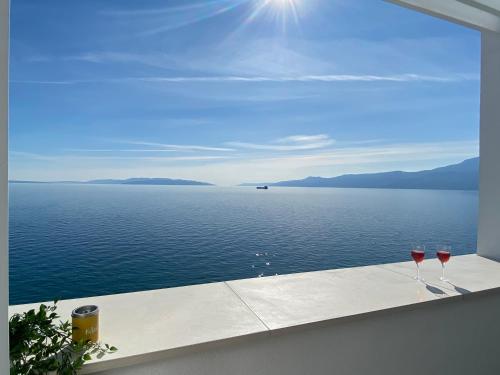 two wine glasses sitting on a ledge overlooking the water at RIA Lungomare in Rijeka