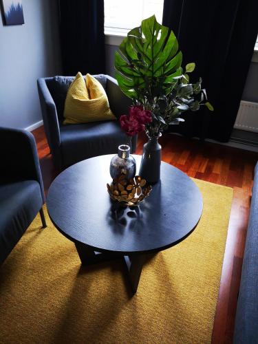 a black coffee table with a vase and flowers on it at First Hotel Millennium in Oslo