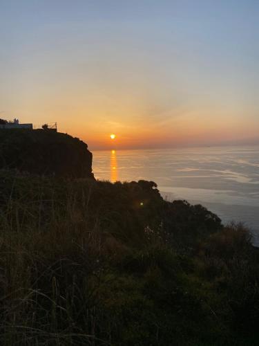 a sunset over the ocean with the sun on a hill at Villa Mareblu Luxury Holiday Apartment direttamente sul mare in Stromboli